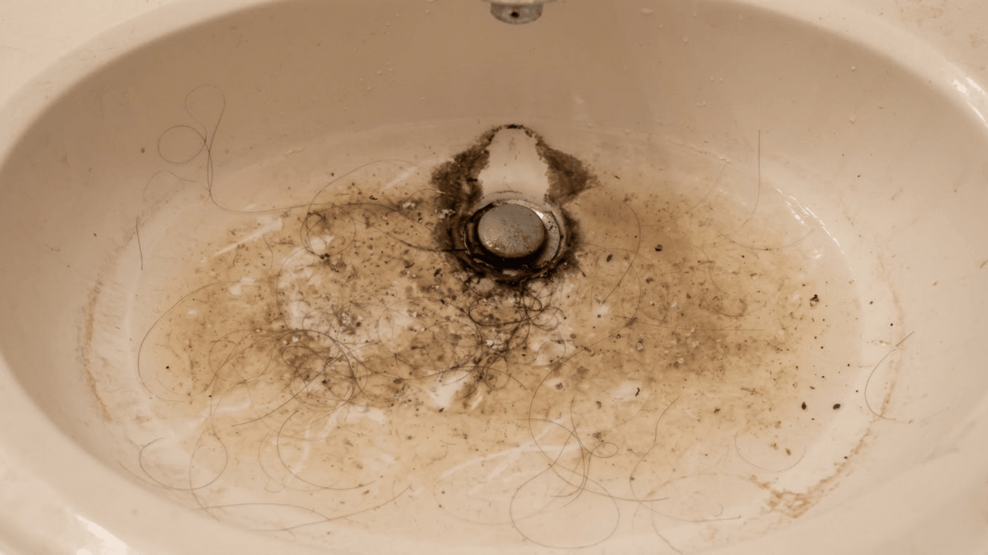 hair and debris buildup around bathroom sink drain causing a clogged basin