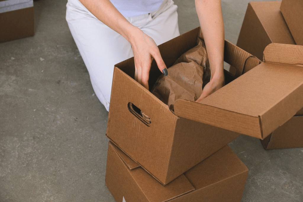 Person packing items into cardboard boxes on concrete floor